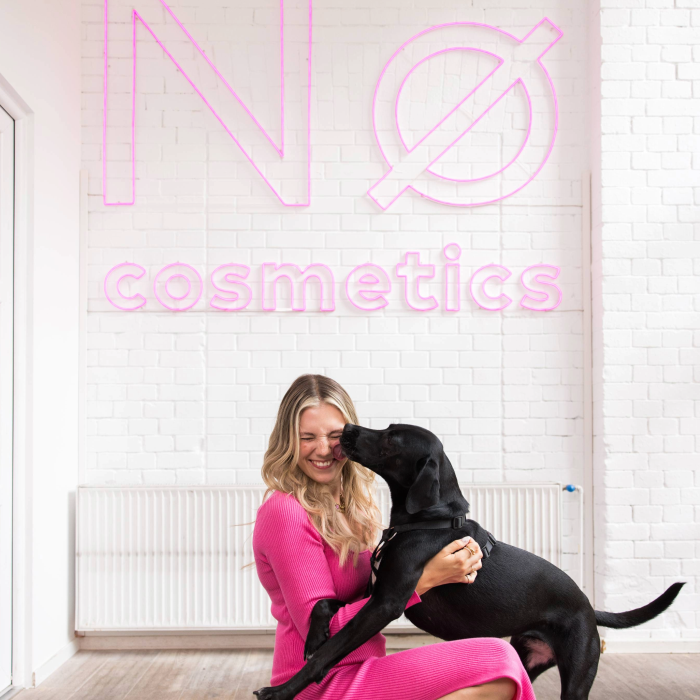 Caroline Kroll mit einem Hund vor dem Nø Cosmetics Logo