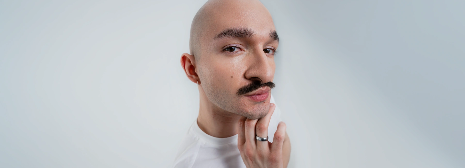 Porträt eines Mannes mit leichtem Hautunreinheiten-Bereich am Kinn, der nachdenklich sein Gesicht berührt.