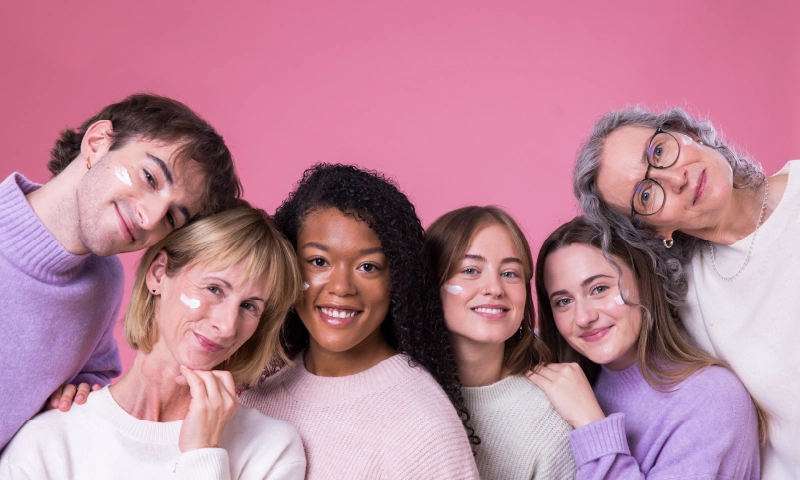 Sechs lächelnde Personen mit Skincare im Gesicht