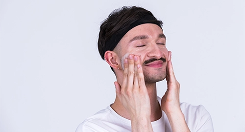 Person massiert sanft Gesichtsreinigung in das Gesicht ein