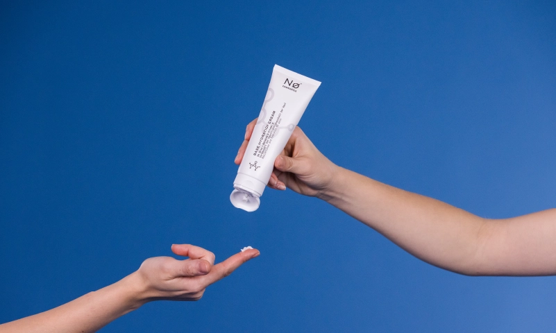 Eine Hand, die Creme aus einer Tube auf eine andere Hand drückt