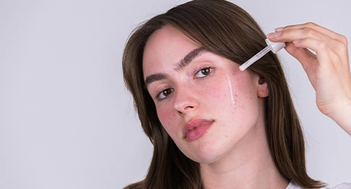 Person trägt ein Serum auf das Gesicht auf