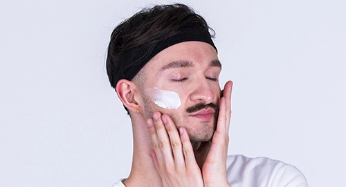 Person trägt Sonnenschutz auf das Gesicht auf