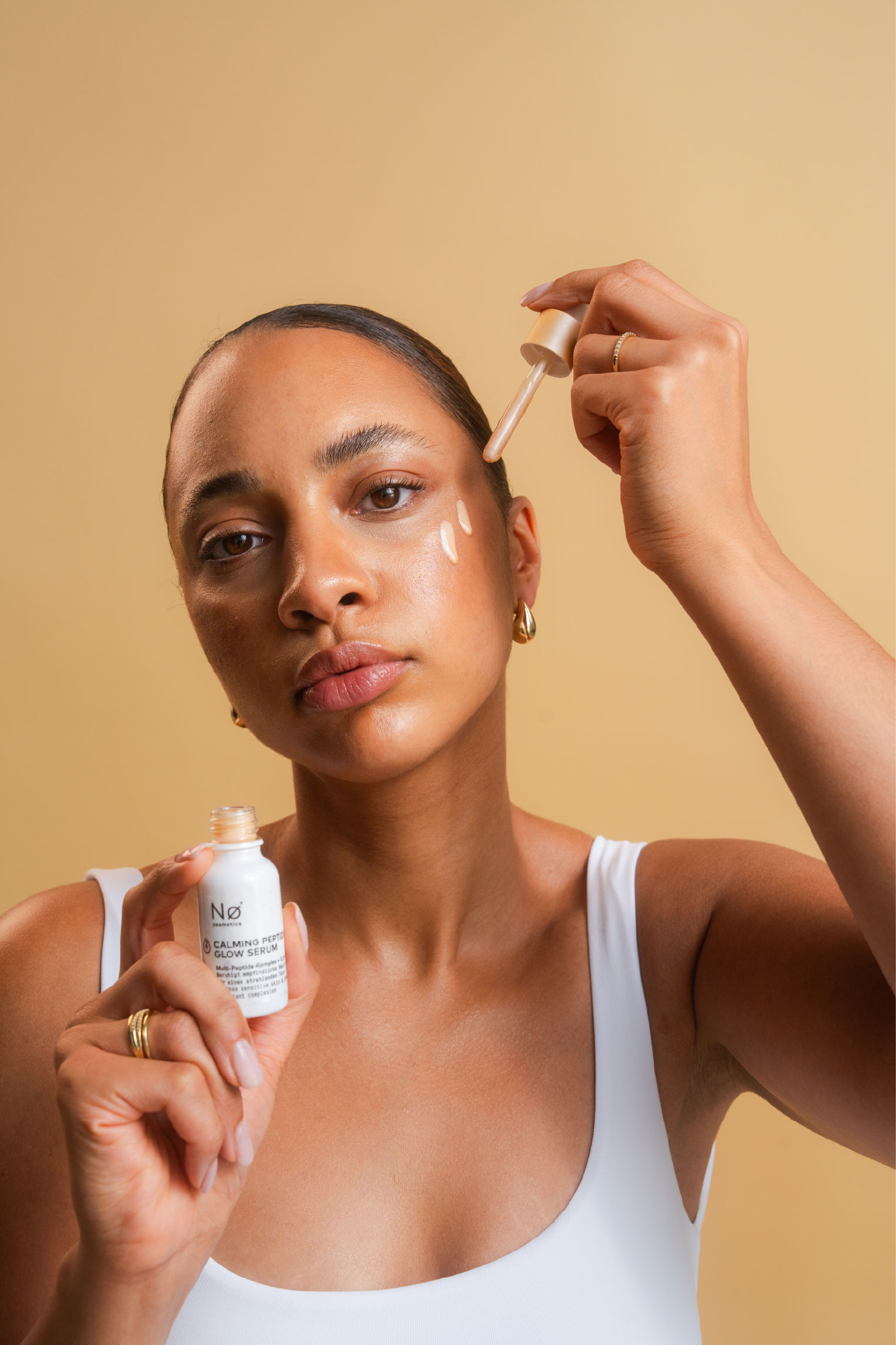 Person trägt das Calming Peptide Glow Serum auf ihr Gesicht auf